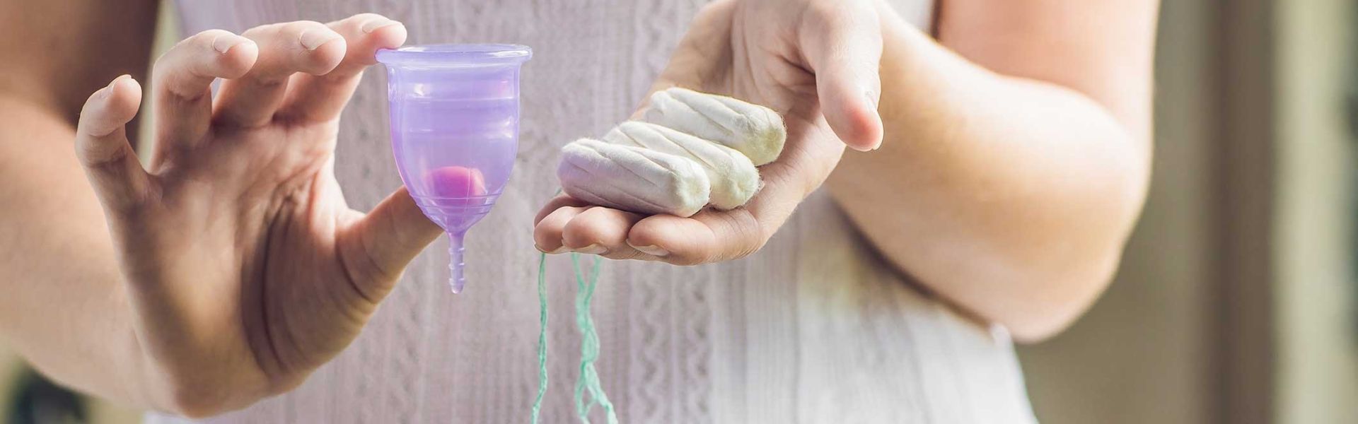 Une femmes tenant une coupe menstruelle et des tampons